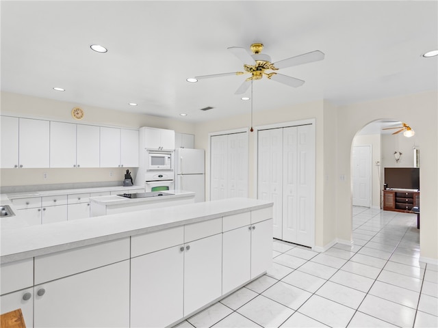 kitchen featuring white appliances, a ceiling fan, light tile patterned flooring, arched walkways, and light countertops