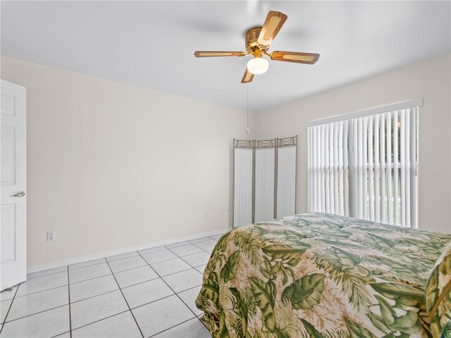 bedroom featuring light tile patterned floors, a ceiling fan, and baseboards