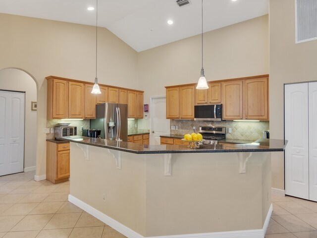 kitchen featuring high vaulted ceiling, appliances with stainless steel finishes, light tile patterned floors, and a kitchen island with sink