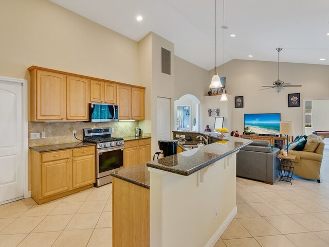 kitchen featuring a center island with sink, appliances with stainless steel finishes, ceiling fan, high vaulted ceiling, and hanging light fixtures