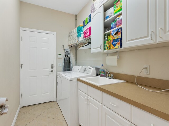 washroom featuring washing machine and dryer, cabinets, sink, and light tile patterned floors