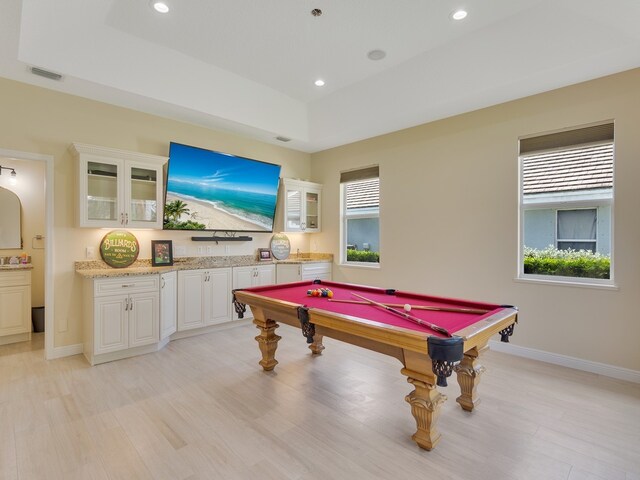 game room with pool table, light hardwood / wood-style floors, and a raised ceiling