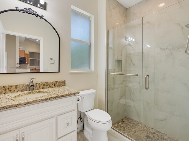 bathroom with toilet, vanity, and a shower with shower door