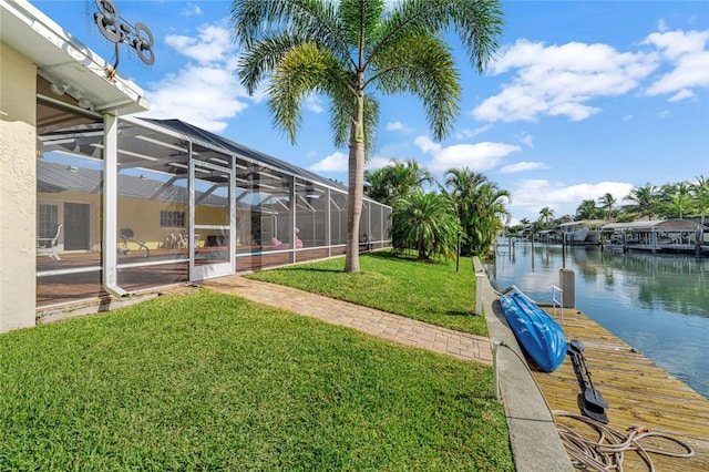 view of yard with glass enclosure, a water view, and a boat dock