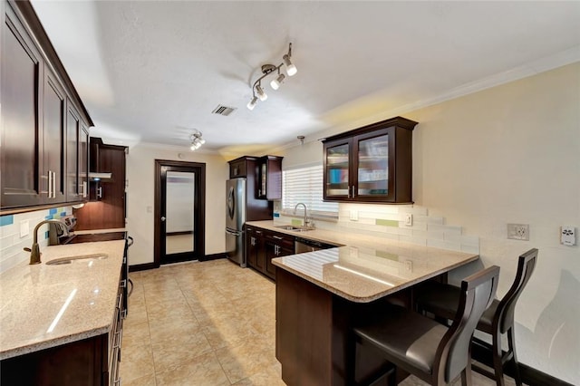 kitchen featuring kitchen peninsula, light stone counters, crown molding, and sink