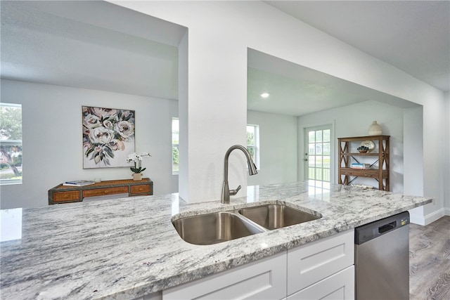 kitchen featuring dishwasher, sink, white cabinets, light stone countertops, and light hardwood / wood-style flooring