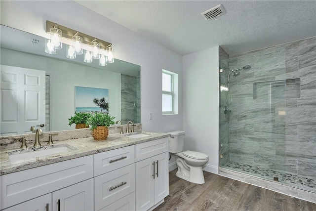 bathroom with vanity, tiled shower, hardwood / wood-style floors, and a textured ceiling