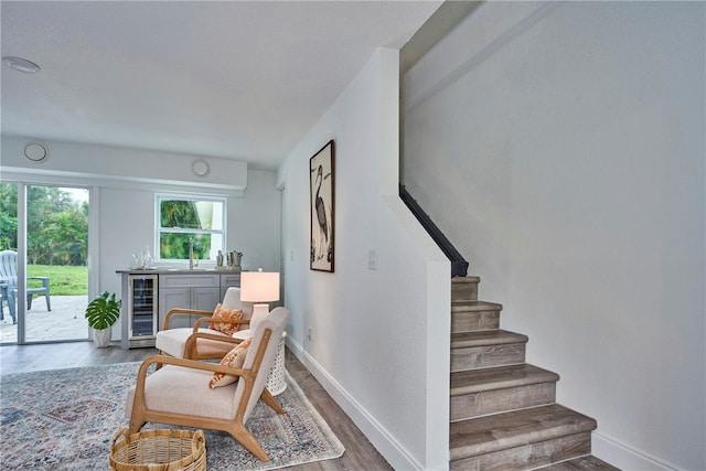 stairs with hardwood / wood-style floors, beverage cooler, and indoor wet bar