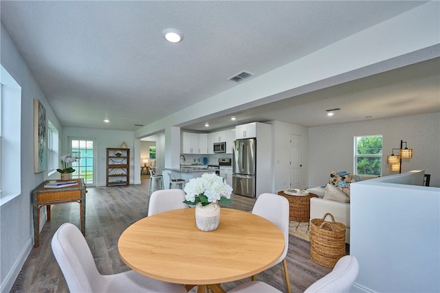 dining space with a wealth of natural light, dark hardwood / wood-style floors, and a textured ceiling