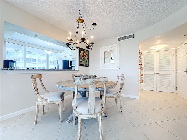 dining room featuring light tile patterned flooring, a textured ceiling, and an inviting chandelier