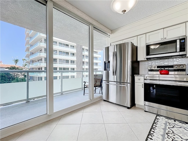 kitchen with white cabinetry, a textured ceiling, light tile patterned floors, and stainless steel appliances