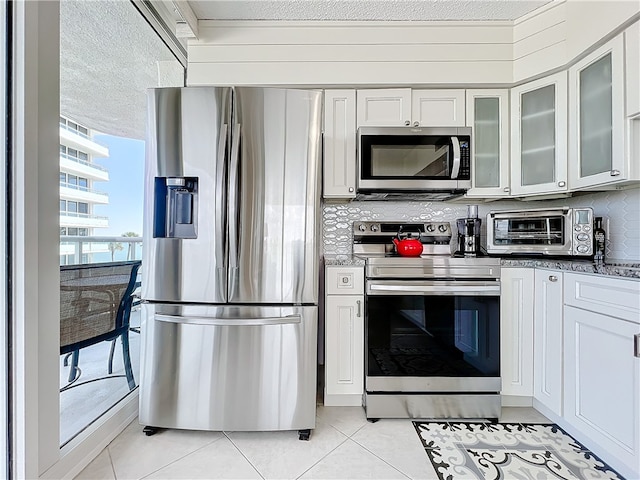 kitchen with white cabinetry, appliances with stainless steel finishes, a textured ceiling, and light tile patterned flooring