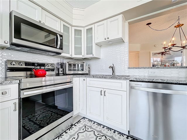 kitchen with stainless steel appliances, a textured ceiling, sink, an inviting chandelier, and white cabinets