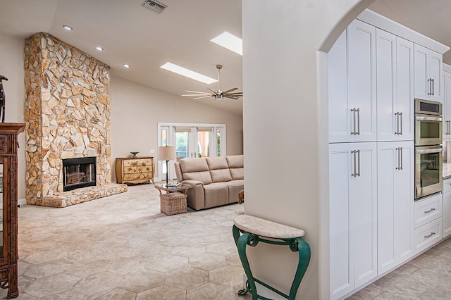 living room featuring ceiling fan, a fireplace, and lofted ceiling