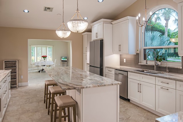 kitchen featuring appliances with stainless steel finishes, a kitchen island, sink, decorative light fixtures, and white cabinetry