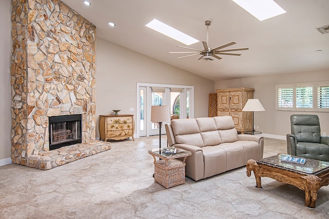 living room featuring a skylight, a stone fireplace, a wealth of natural light, and ceiling fan