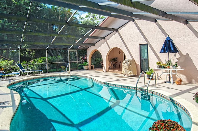 view of pool with glass enclosure, grilling area, and a patio area