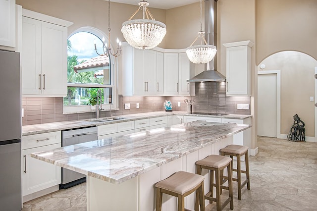 kitchen featuring white cabinetry, stainless steel appliances, light stone counters, a notable chandelier, and a kitchen island