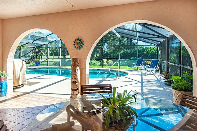 view of pool featuring glass enclosure and a patio area