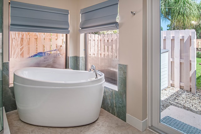 bathroom with tile patterned floors, a tub to relax in, and tile walls