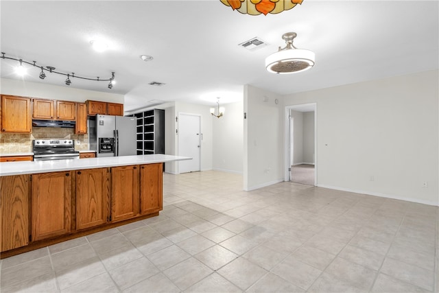 kitchen with decorative backsplash, appliances with stainless steel finishes, and an inviting chandelier