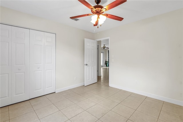 unfurnished bedroom with light tile patterned floors, a closet, and ceiling fan