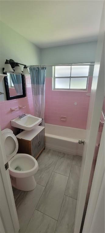 full bathroom with toilet, shower / bathtub combination with curtain, and sink