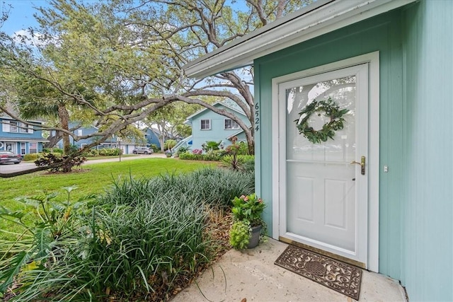 view of exterior entry featuring a lawn