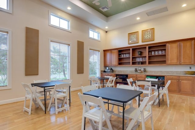 dining space featuring ceiling fan, light hardwood / wood-style floors, and a high ceiling