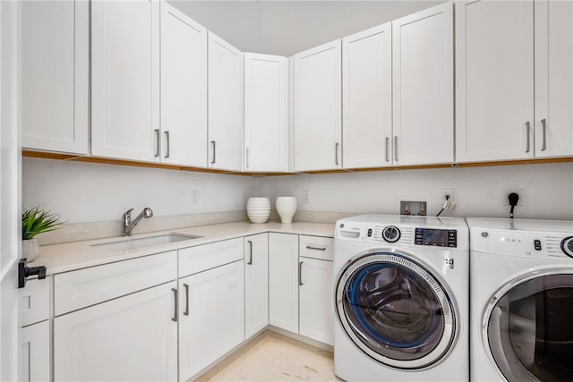 clothes washing area with washing machine and clothes dryer, cabinets, and sink