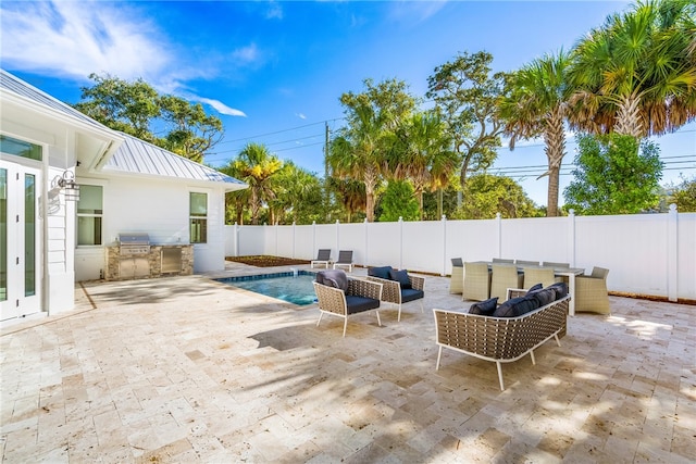 view of patio / terrace with a grill, outdoor lounge area, a fenced in pool, and exterior kitchen