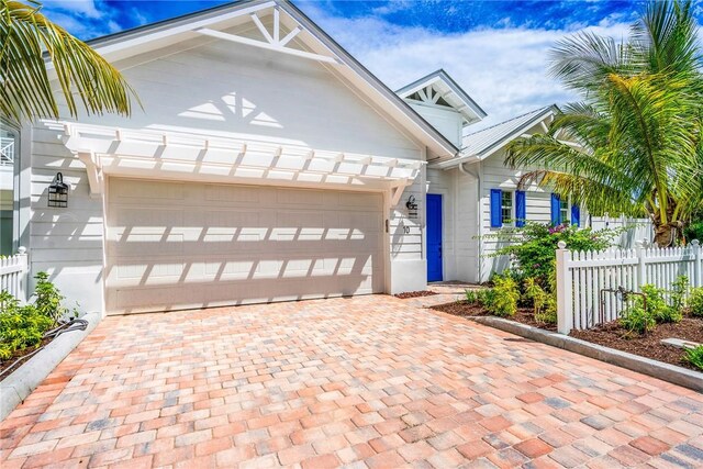 10 Strand Dr, Vero Beach, FL 32963 - view of front facade featuring fence, decorative driveway, and a garage