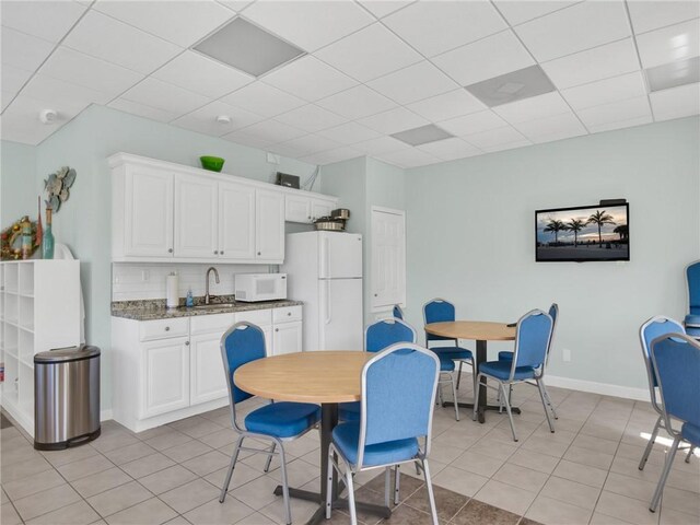 dining area featuring a drop ceiling, light tile patterned flooring, and sink