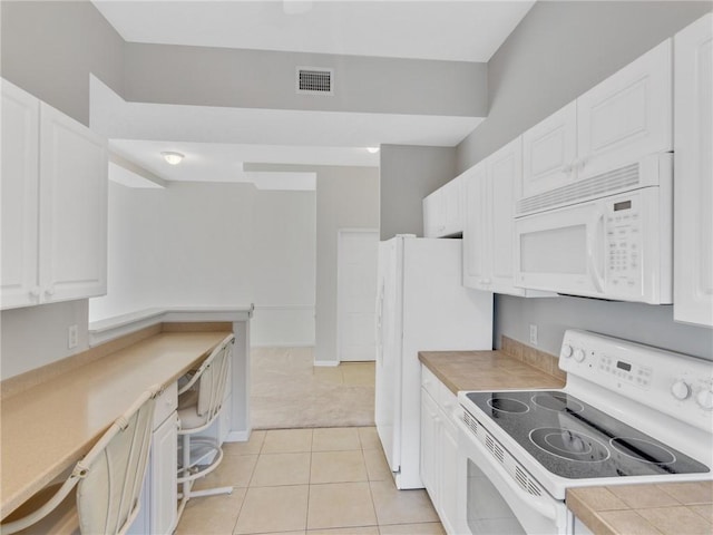 kitchen featuring tile counters, white cabinets, light tile patterned flooring, and white appliances