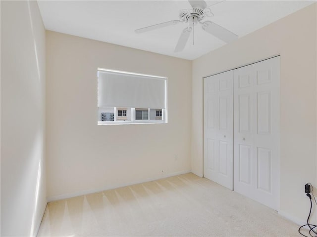 unfurnished bedroom with ceiling fan, a closet, and light colored carpet