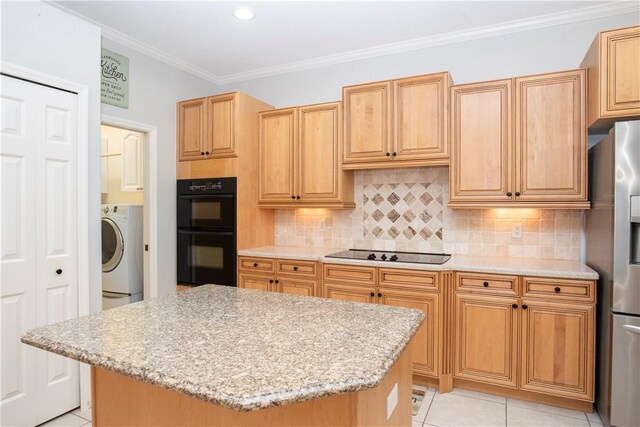 kitchen featuring light stone counters, washer / clothes dryer, black appliances, and a kitchen island