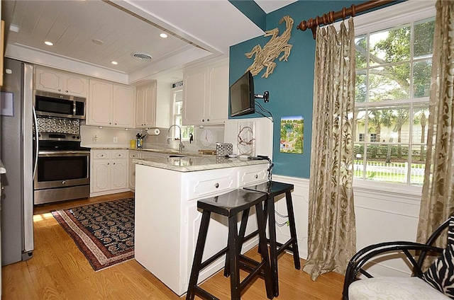 kitchen featuring a raised ceiling, white cabinetry, and appliances with stainless steel finishes