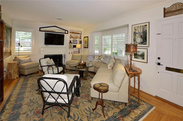 living room featuring hardwood / wood-style flooring, ornamental molding, and built in shelves