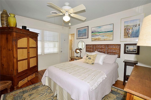 bedroom with ornamental molding, dark wood-type flooring, and ceiling fan