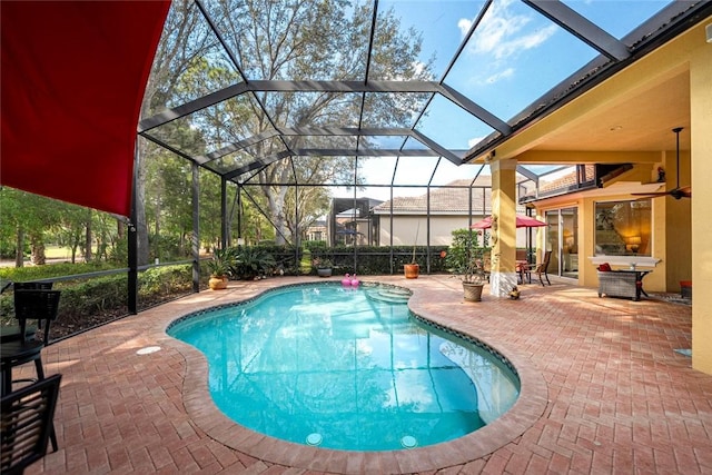 outdoor pool featuring glass enclosure and a patio