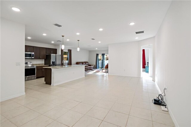 8646 102nd Ave, Vero Beach, FL 32967 - kitchen featuring appliances with stainless steel finishes, open floor plan, dark brown cabinets, an island with sink, and recessed lighting