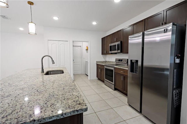 8646 102nd Ave, Vero Beach, FL 32967 - kitchen with stainless steel appliances, a sink, dark brown cabinets, light tile patterned flooring, and decorative light fixtures