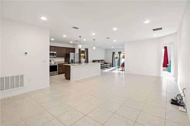 8646 102nd Ave, Vero Beach, FL 32967 - kitchen featuring appliances with stainless steel finishes, open floor plan, dark brown cabinetry, a center island with sink, and decorative light fixtures