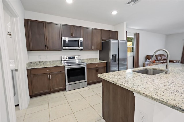 8646 102nd Ave, Vero Beach, FL 32967 - kitchen featuring stainless steel appliances, a sink, dark brown cabinetry, light tile patterned flooring, and light stone counters