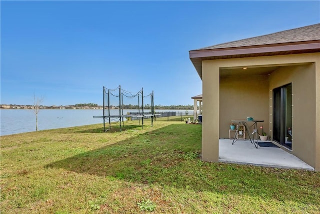 view of yard with a water view, a patio area, and a trampoline