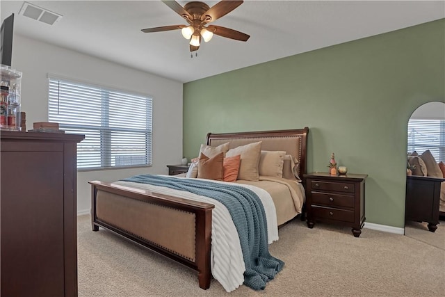 bedroom with ceiling fan, light colored carpet, and multiple windows