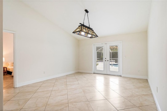 tiled spare room featuring french doors and lofted ceiling