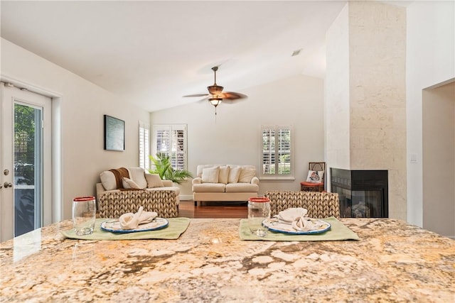 living room featuring a tiled fireplace, vaulted ceiling, hardwood / wood-style floors, and ceiling fan