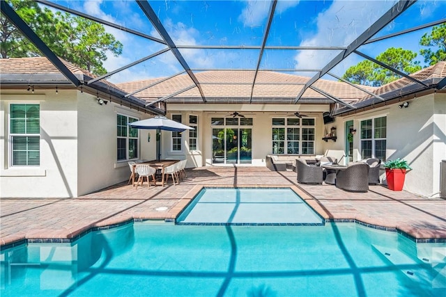 pool with ceiling fan, glass enclosure, a patio area, and an outdoor hangout area