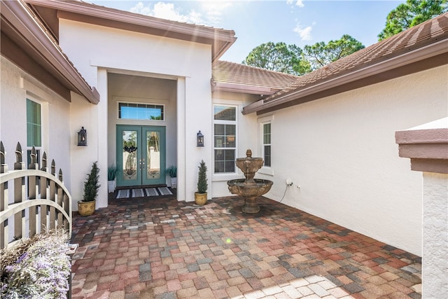 property entrance featuring a tile roof, french doors, and stucco siding